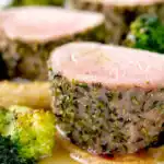 Close up roast pork fillet served with apple puree, roast parsnips and broccoli.