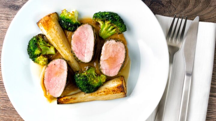 Roast pork fillet served with apple puree, cider sauce, roast parsnips, and broccoli.