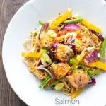 Overhead salmon stir fry with egg noodles and vegetables featuring a title overlay.