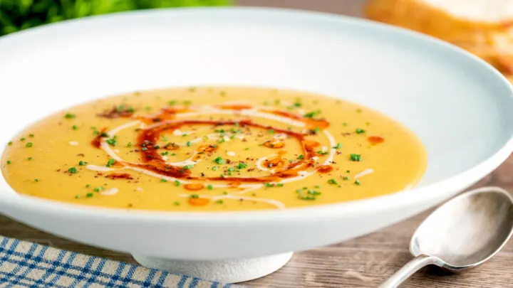 Turkish lentil soup or mercimek corbasi with paprika butter and tahini swirls, sumac & chives.