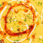 Close up Turkish lentil soup or mercimek corbasi with paprika butter and tahini swirls.