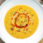 Overhead Turkish lentil soup or mercimek corbasi with paprika butter and tahini swirls.