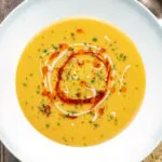 Overhead Turkish lentil soup or mercimek corbasi with paprika butter and tahini swirls.
