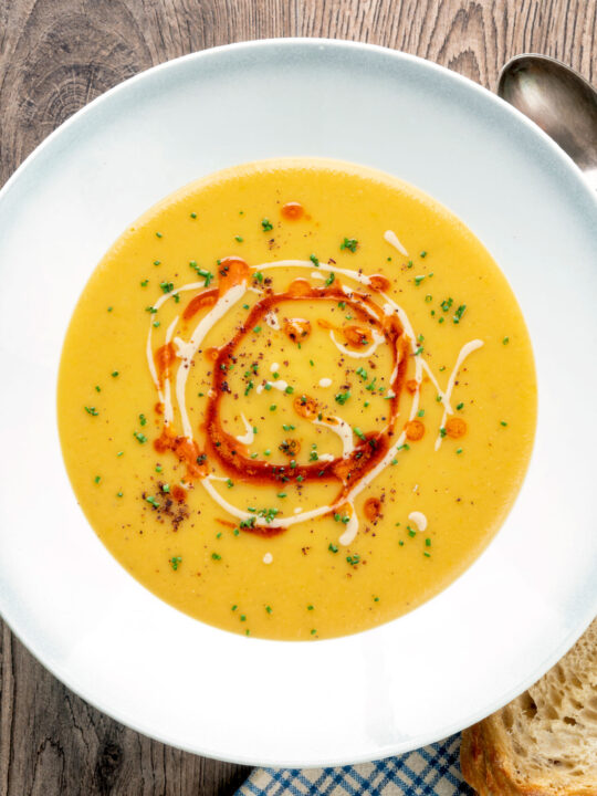 Overhead Turkish lentil soup or mercimek corbasi with paprika butter and tahini swirls.