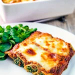 Goats cheese cannelloni stuffed spinach under a tomato and cheese crust served on a plate.