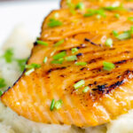 Close up pan fried honey mustard salmon served on celeriac mash.