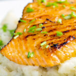 Close up pan fried honey mustard salmon served on celeriac mash featuring a title overlay.