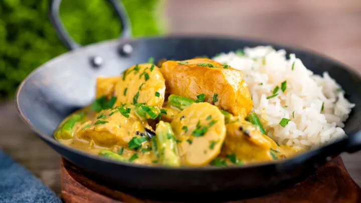 Keralan fish curry with coconut milk featuring green beans and potato in an iron karai.
