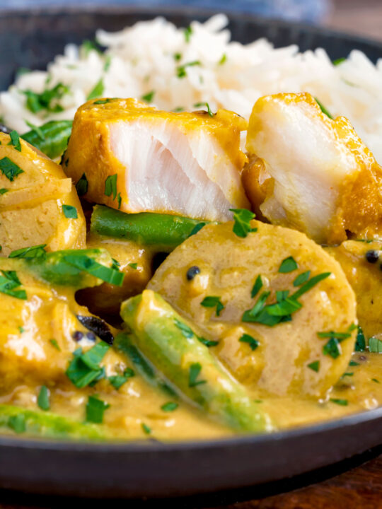 Keralan fish curry with coconut milk showing the texture of the cooked white fish.