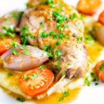 Rabbit Cacciatore or Coniglio alla Cacciatora with shallot and cherry tomatoes on polenta.