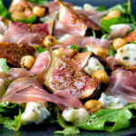 Roasted figs with prosciutto ham, rocket, blue cheese and hazelnuts featuring a title overlay.