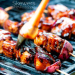 BBQ chicken skewers with pineapple & red onion cooking on a barbecue featuring a title overlay.