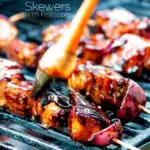 BBQ chicken skewers with pineapple & red onion cooking on a barbecue featuring a title overlay.