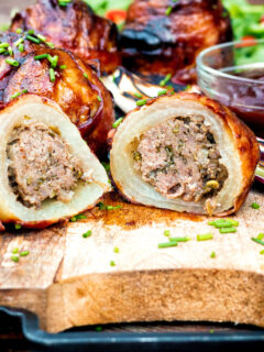 Stuffed onions wrapped in bacon & BBQ sauce cut open showing beef stuffing.