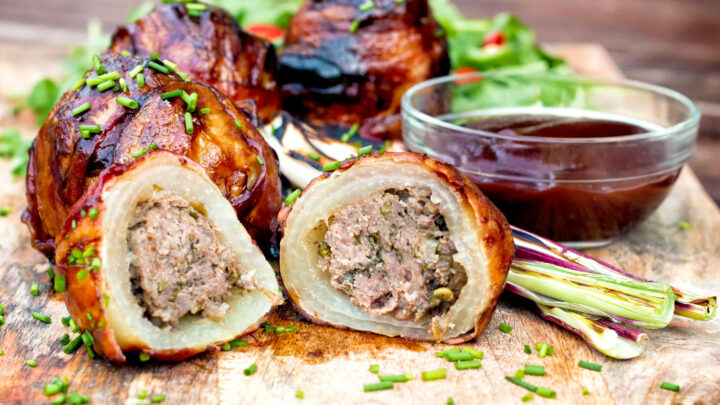 Overhead stuffed onions wrapped in bacon & BBQ sauce glaze with a salad.