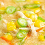 Close up Chinese style chicken and sweetcorn soup with spring onion featuring a title overlay.