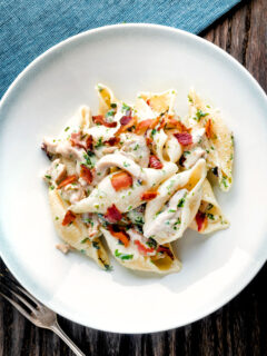 Overhead creamy chicken and bacon pasta served in a white bowl.