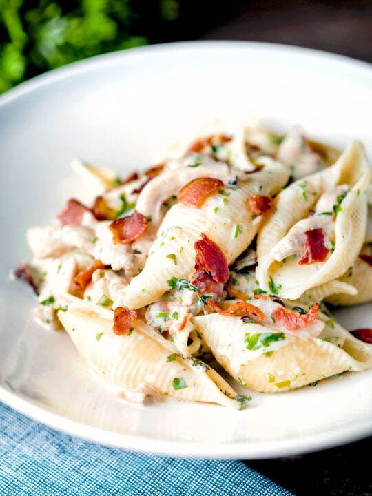 Creamy chicken and bacon pasta served in a white bowl.