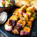 Paneer tikka kebab skewers served with kachumber salad and naan bread featuring a title overlay.