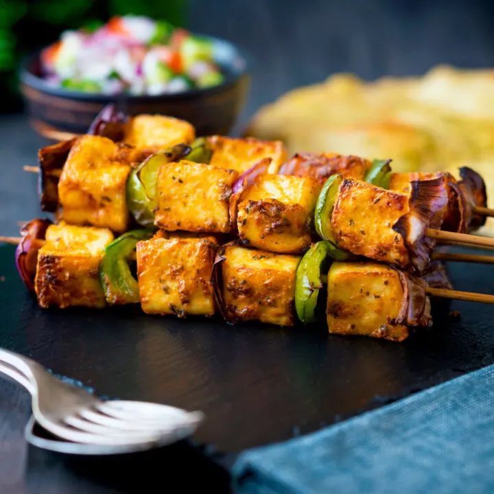 Paneer tikka skewers served with kachumber salad and naan bread.