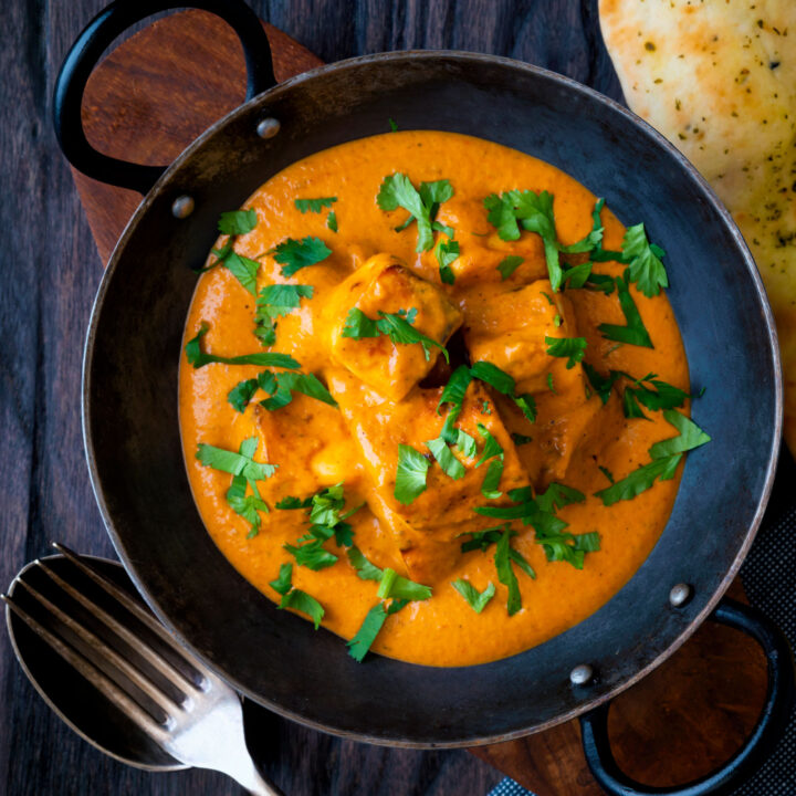 Paneer tikka masala curry served in an iron karai with fresh coriander.