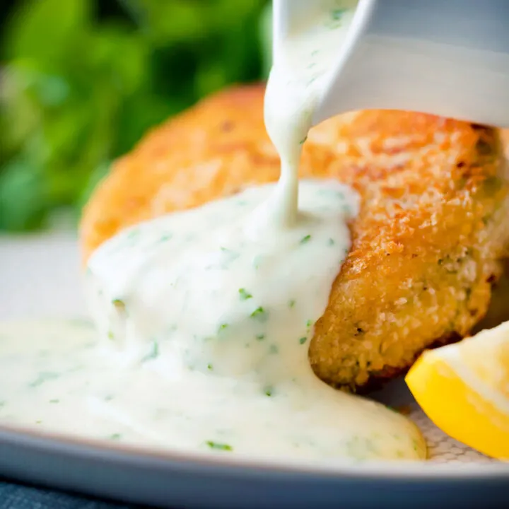 White parsley sauce poured over a fishcake.