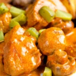 Close up pork tenderloin stroganoff with mushrooms and chopped pickles.