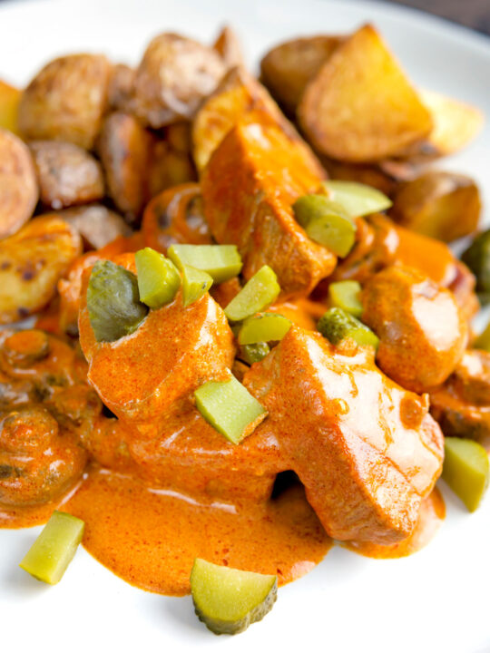 Close up pork tenderloin stroganoff with mushrooms and fried potatoes.