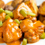 Close up pork tenderloin stroganoff with mushrooms, fried potatoes and pickles.