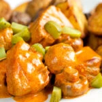 Close up pork tenderloin stroganoff with mushrooms, fried potatoes and pickles.