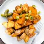 Overhead pork tenderloin stroganoff with mushrooms, fried potatoes and pickles.