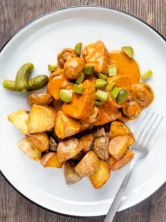 Overhead pork tenderloin stroganoff with mushrooms, fried potatoes and pickles.