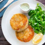 Overhead smoked haddock fishcakes served with with parsley sauce.