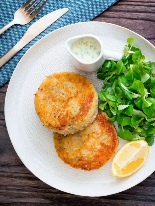 Overhead smoked haddock fishcakes served with with parsley sauce.