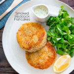 Overhead smoked haddock fishcakes served with with parsley sauce featuring a title overlay.