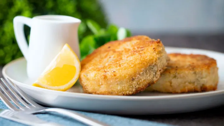 Close up smoked haddock fishcakes served with a wedge of lemon.