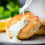 Close up smoked haddock fishcakes served with parsley sauce.