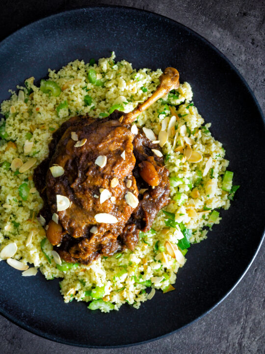 Overhead tamarind duck leg with a date and almond sauce served with couscous.