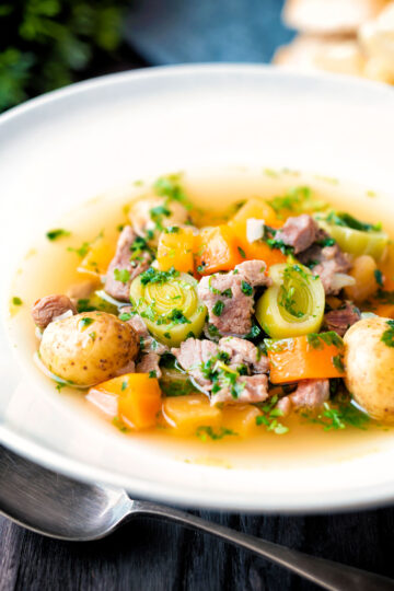 Welsh cawl, a lamb and vegetable broth based soup in a white bowl.