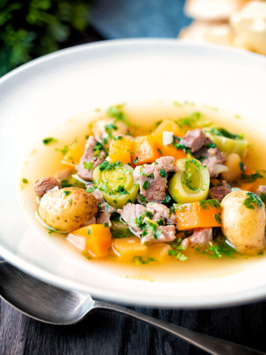 Welsh cawl, a lamb and vegetable broth based soup in a white bowl.