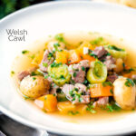 Welsh cawl, a lamb and vegetable broth based soup in a white bowl featuring a title overlay.