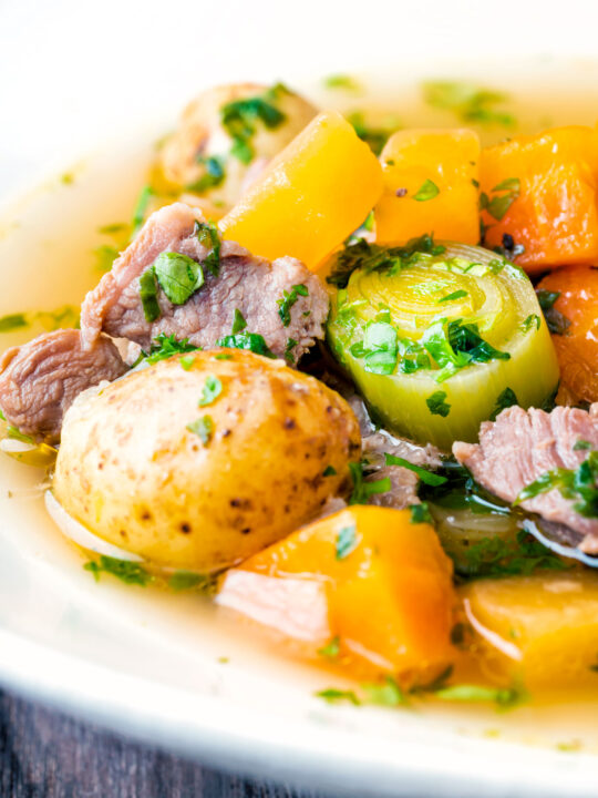 Close up Welsh cawl, a lamb and vegetable broth based soup in a white bowl.