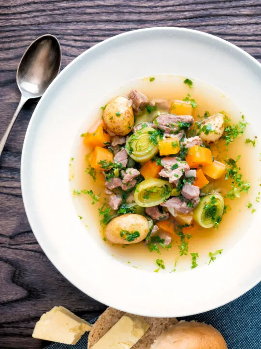 Close up Welsh cawl, a lamb and vegetable broth based soup served with bread and cheese.