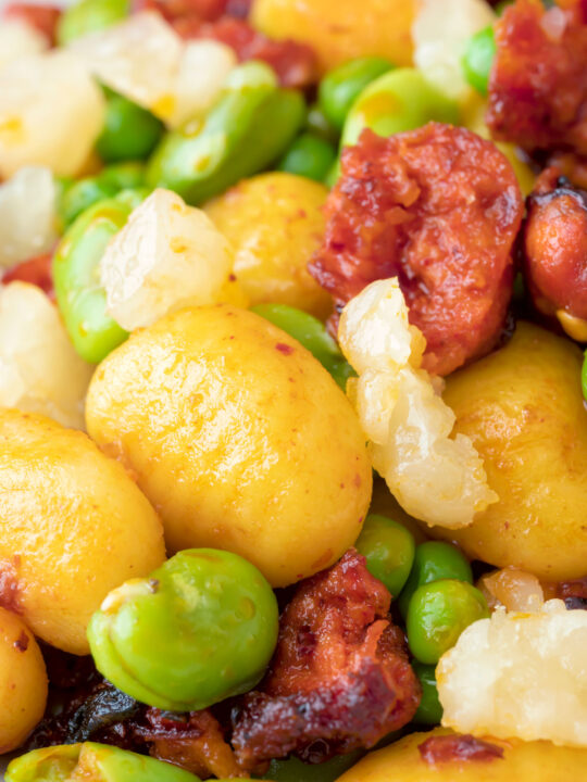 Close up chorizo gnocchi with green peas and broad beans.