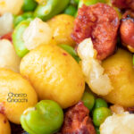 Close up chorizo gnocchi with green peas and broad beans featuring a title overlay.