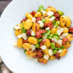 Overhead chorizo gnocchi with green peas, broad beans and manchego cheese.