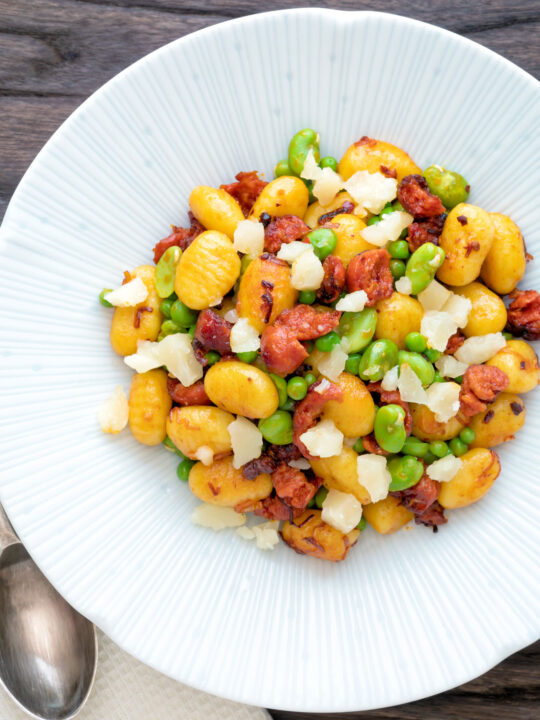 Overhead chorizo gnocchi with green peas, broad beans and manchego cheese.