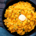 Overhead swede and carrot mash with a knob of butter in a black bowl featuring a title overlay.