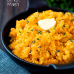 Swede and carrot mash with a knob of butter in a black bowl featuring a title overlay.