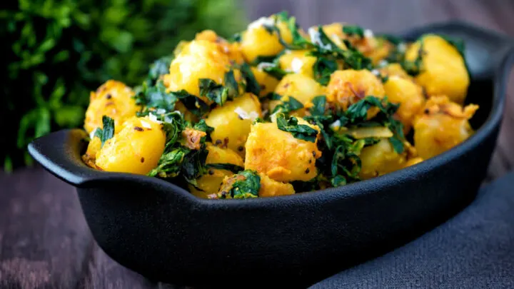 Indian aloo methi or fenugreek potatoes served in a black dish.